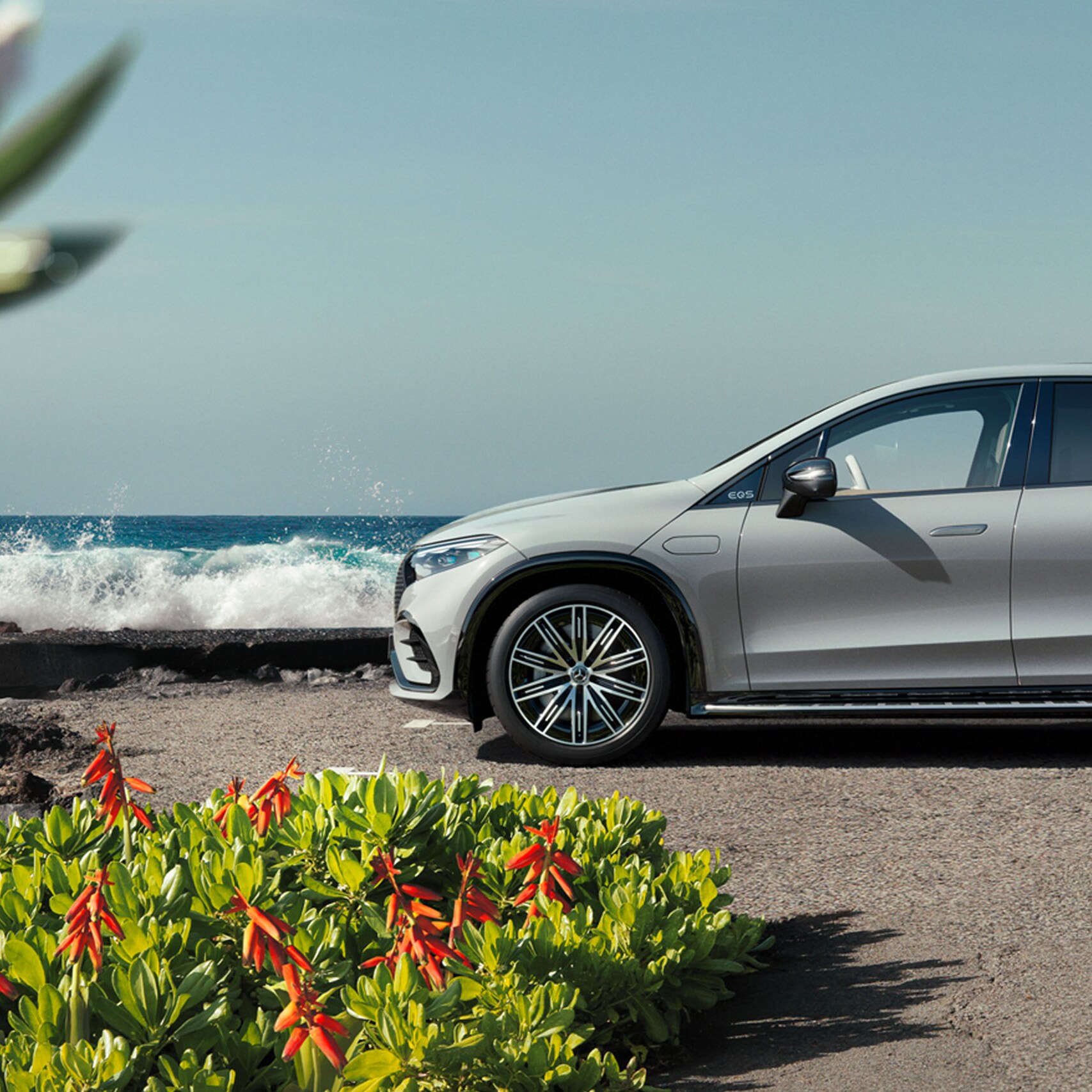EQS SUV by Mercedes-EQ parked sideways at parking lot in front of the sea.