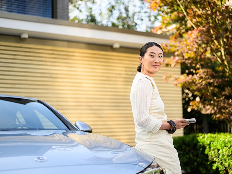 A person leaning against a Mercedes-Benz vehicle, looking at the camera and holding a mobile device 一個人靠在賓士車上拿著手機並看著鏡頭