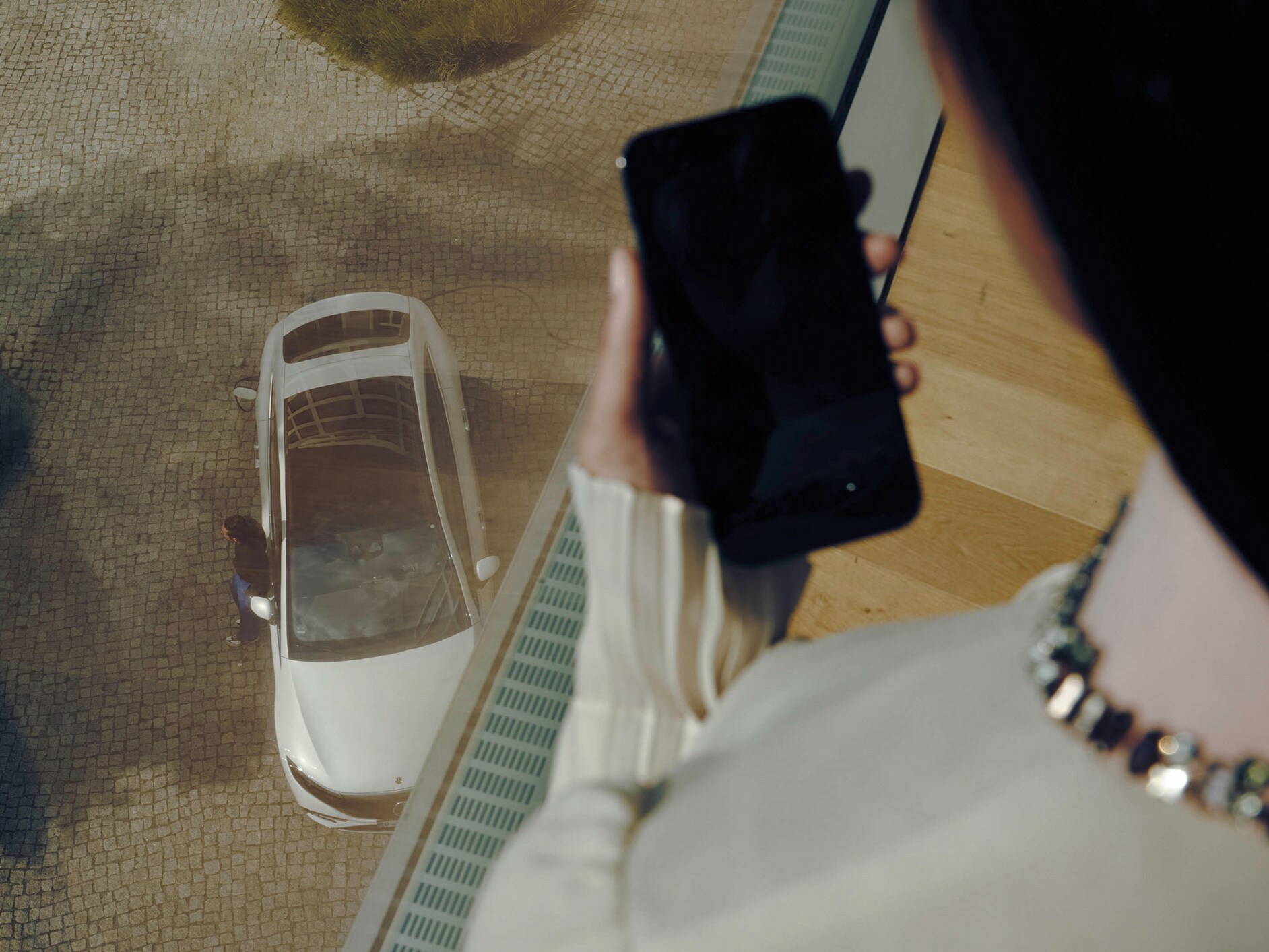 一位女士在白色賓士EQS旁邊用手機